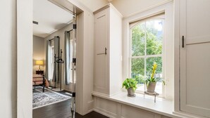 A hallway with a large window, a bed, and a lamp.