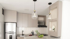 A modern kitchen with a stainless steel refrigerator, a marble countertop, and two gold-framed stools. - Bocagrande - 2BR with panoramic ocean view (Cartagena de Indias)