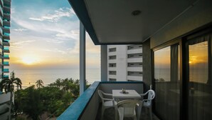 A balcony with a table and chairs, overlooking a sunset over the ocean. - Bocagrande - 2BR with panoramic ocean view (Cartagena de Indias)