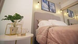 A neatly arranged hotel room with a bed, a bedside table with a plant, and wall-mounted artwork. - Bocagrande - 2BR with panoramic ocean view (Cartagena de Indias)