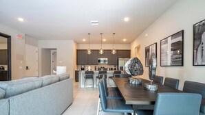 Une cuisine moderne avec des meubles de couleur sombre, un îlot central et des luminaires suspendus.