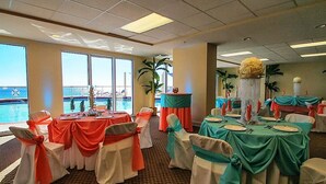 A banquet hall with tables set for a formal event, large windows offering a view of the ocean, and a decorative centerpiece on each table. - SUNRISE BEACH 2105, 2 BED 2 BA. balcony hOt TUB PoolS! (panama city beach)