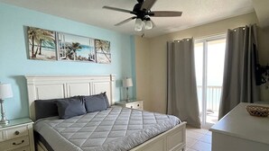 A bedroom with a bed, nightstands, a ceiling fan, and a window with curtains. - SUNRISE BEACH 2105, 2 BED 2 BA. balcony hOt TUB PoolS! (panama city beach)