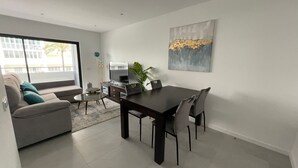 Un salon moderne comprenant un canapé, une table basse, un téléviseur et une table à manger.
