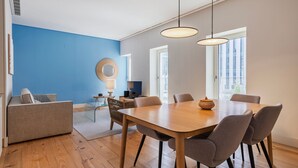 A modern dining area with a wooden table, grey upholstered chairs, and a blue accent wall.