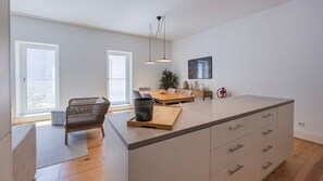 Una cocina moderna con una isla grande, suelo de madera e iluminación colgante.