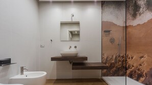 Une salle de bain moderne avec une baignoire sur pieds, un lavabo mural avec un vasque et une douche à parois de verre.