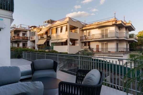 A residential building with balconies, outdoor seating, and a gated entrance.