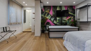 Un dormitorio moderno con cama, televisor y una planta grande.