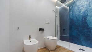 Un baño moderno con bidé, inodoro y ducha con cerramiento de vidrio.