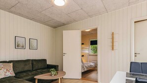Une pièce chaleureuse avec un canapé vert, une petite table en bois et un lit dans la pièce adjacente.