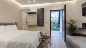 Una habitación de hotel moderna con una cama grande, zona de estar y balcón con vistas a la ciudad.