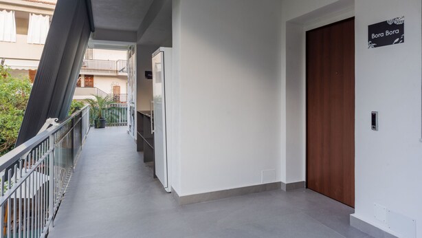 Un pasillo con una puerta de madera que dice "Bora Bora" y una barandilla de metal.