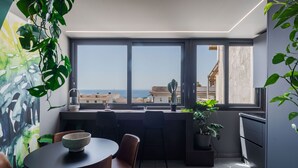 A modern kitchen with a large window, a dining area with a table and chairs, and a potted plant.