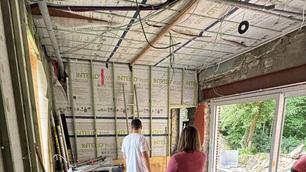 Una obra en construcción con techo y paredes a la vista, herramientas y materiales dispersos.