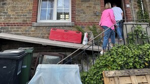 Un edificio de piedra de dos pisos con techo a dos aguas y una entrada principal.