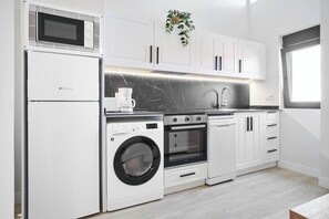 Una cocina moderna con lavadora integrada, horno y microondas.