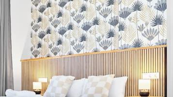 A hotel room with a bed, two bedside lamps, a wooden headboard, and a patterned wallpaper.
