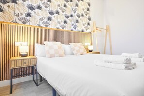 A hotel room with a bed, two bedside tables with lamps, a wooden headboard, and a folded towel on the floor.