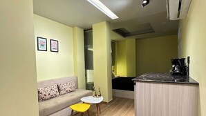 A compact living space with a sofa, a small round table, and a kitchenette area. - Sunrise studio 2 (Delhi)