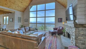 A cozy living room with a large window, a stone fireplace, and a leather sofa.