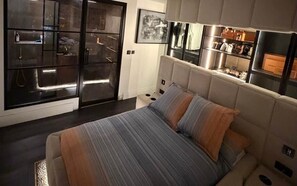 Quarto moderno com cama grande, armário embutido e mesa de cabeceira.