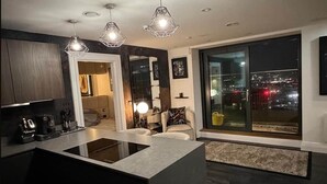 Una cocina moderna con una isla central, iluminación colgante y un amplio ventanal con vistas a la ciudad.