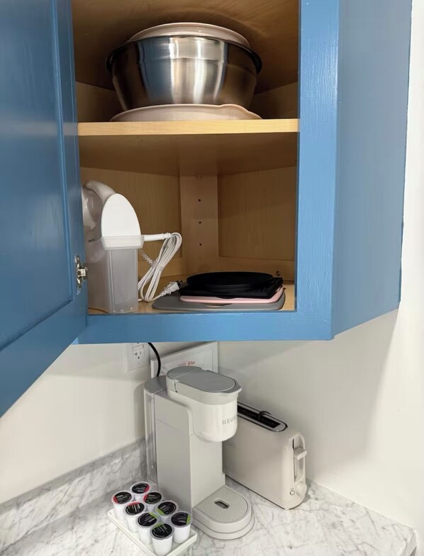 A kitchen with a coffee maker, a toaster, and a kettle.