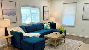 A living room with a blue sectional sofa, a wooden coffee table, and a patterned rug. - Cozy and Convenient- 5 min to Airport (North Charleston)