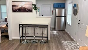 A modern kitchen with a stainless steel refrigerator, a white countertop, and a bar stool area. - Cozy and Convenient- 5 min to Airport (North Charleston)