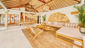 A spacious living area with a high ceiling, a large seating area, and a kitchen in the background.