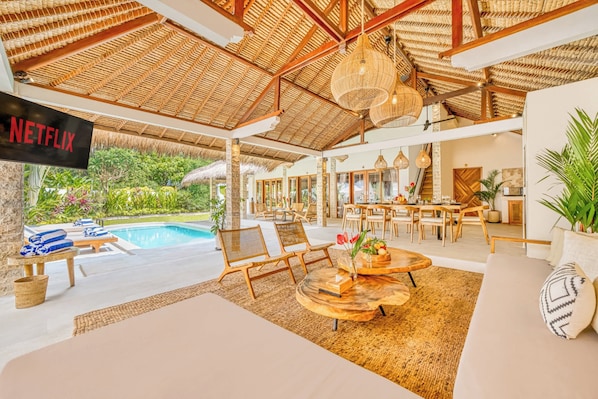 A spacious indoor area with a pool, lounge chairs, and a Netflix sign.