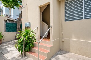 A residential building with a staircase leading to an interior, a potted plant, and a metal railing.