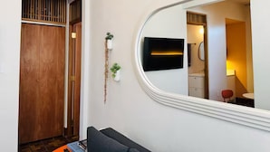 Un pasillo con una puerta de madera, un espejo y una planta pequeña.