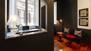 A room with a window, a laptop on a shelf, a lamp, a red table, and a sofa with floral cushions. - SALOTTO BORBONICO - SANFELICE (Naples)
