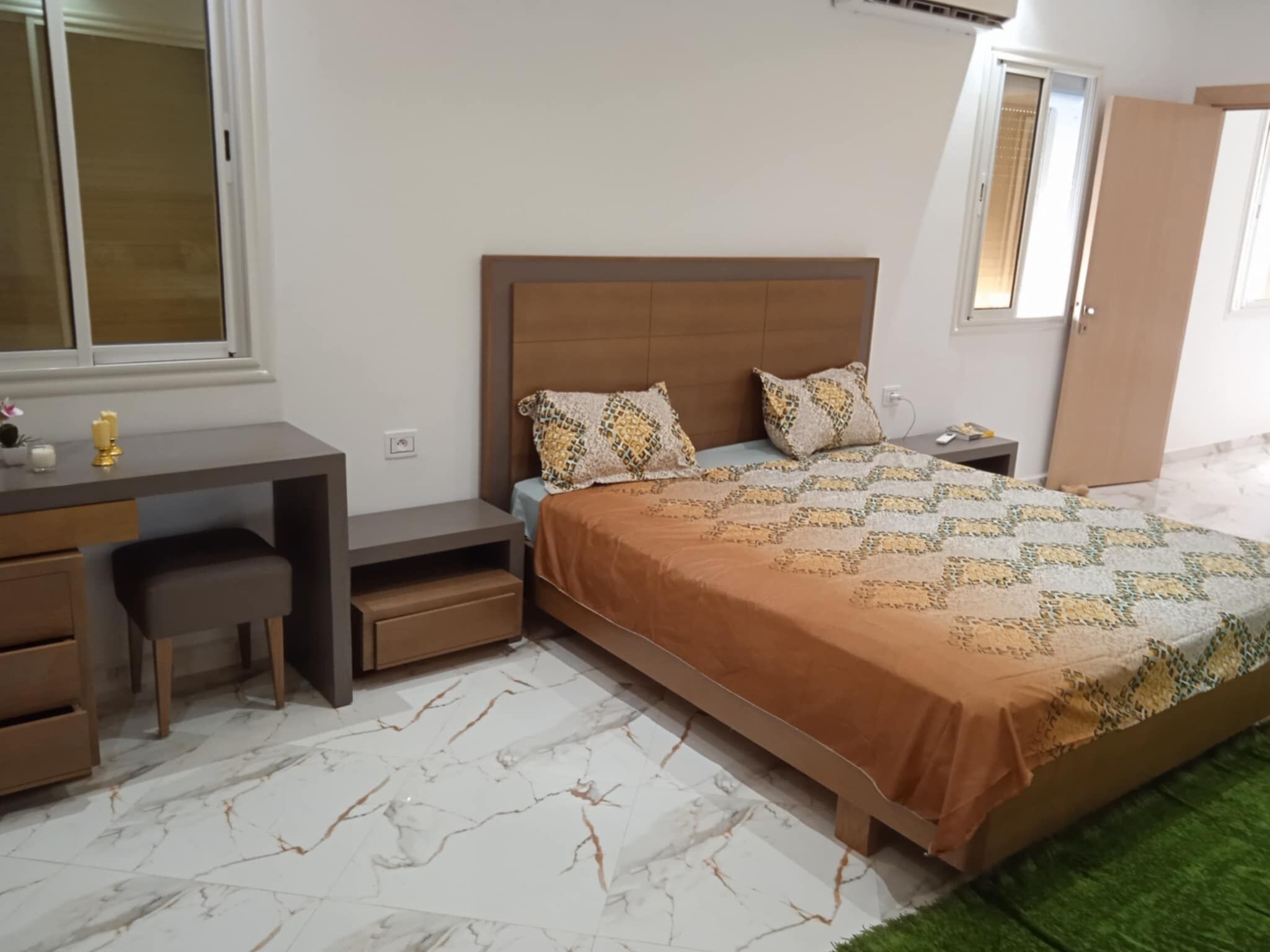 A bedroom with a bed, a desk, and a chair.