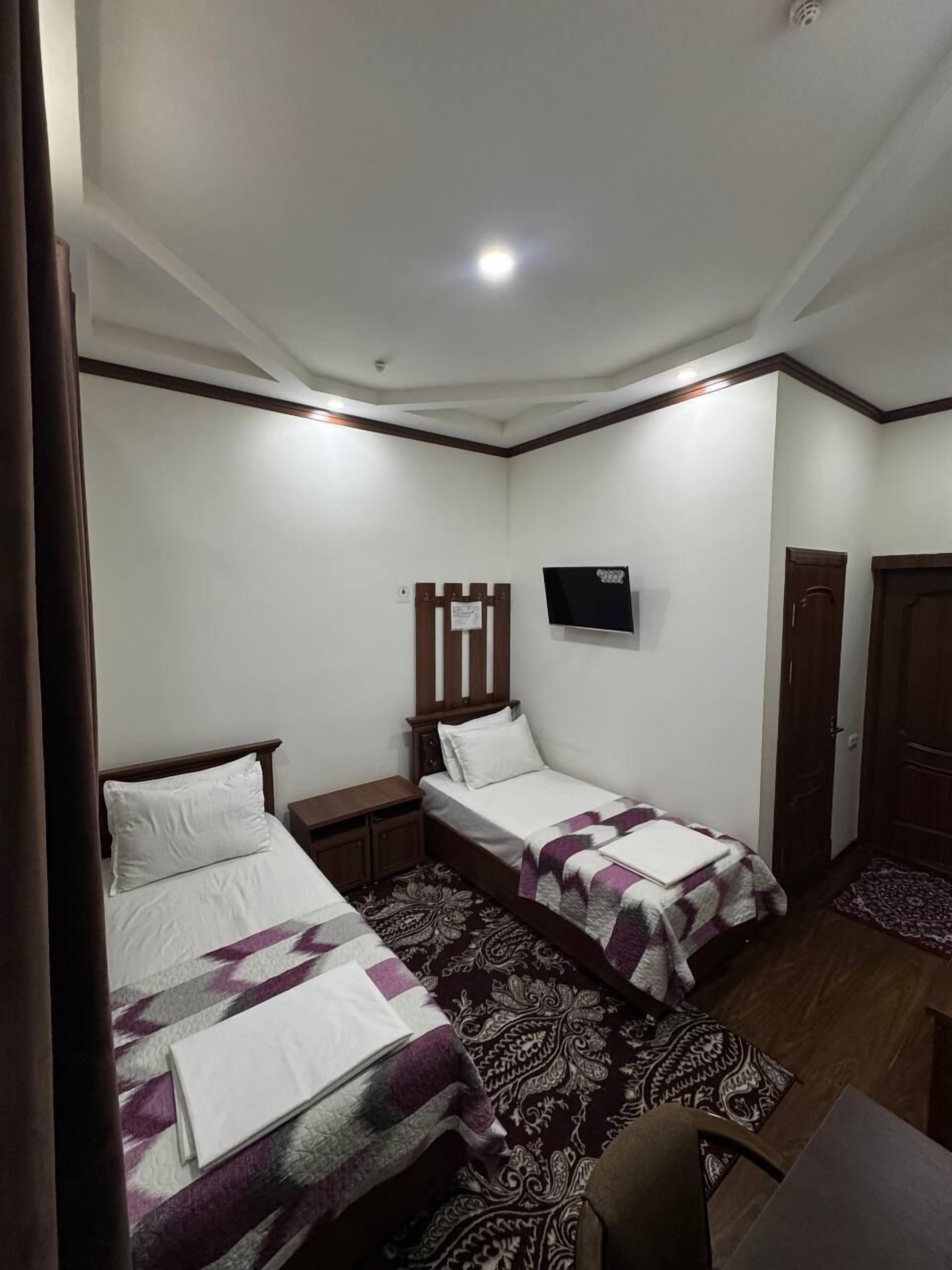 Un dormitorio con dos camas, un televisor en la pared y un cabecero de madera.