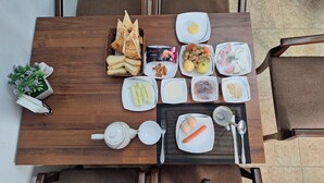 A dining table with various breakfast items including bread, eggs, fruits, and a carrot.