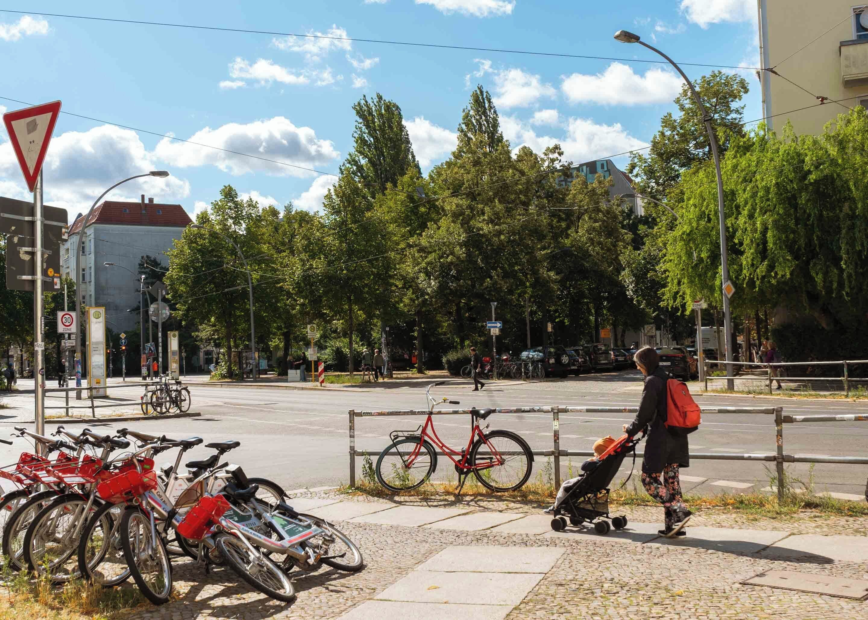 Een straatbeeld met fietsen langs de stoep, een zebrapad en een fietser met een kinderwagen.