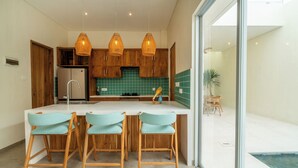 A modern kitchen with wooden cabinets, a white countertop, and three bar stools.