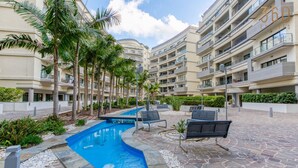A modern hotel with a swimming pool, outdoor seating, and palm trees. - Beautiful 3BR Stay w/private terrace in St Julians (St. Julian`s)