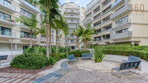 A multi-story residential building with balconies, a landscaped courtyard with benches, and a mix of stone and tiled flooring. - Beautiful 3BR Stay w/private terrace in St Julians (St. Julian`s)