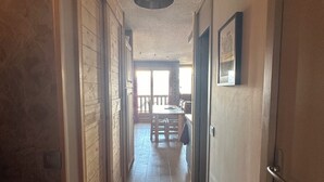 A hallway with wooden floors and walls, leading to a dining area with a table and chairs. - Bright, spacious apartment 100m from village center and ski lift (La Plagne Tarentaise)