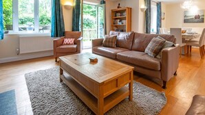 Ein Wohnzimmer mit braunem Ledersofa, einem Holztisch und einem Bücherregal.