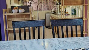 A compact kitchen with wooden cabinets, a dining area with a marble table, and a patterned rug. - Cosy Home in Damansara (Sungai Buloh)