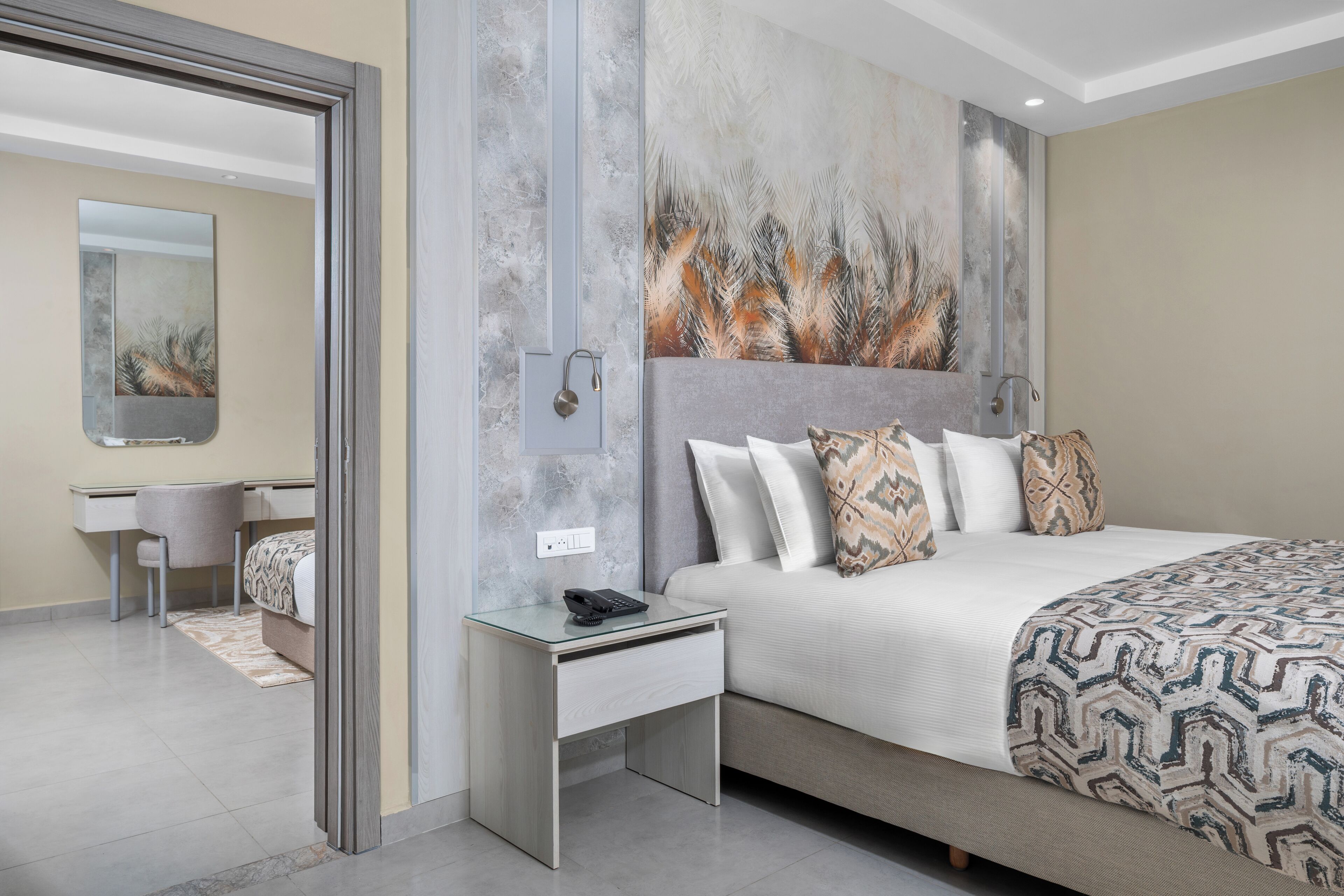 Une chambre d’hôtel moderne, dotée d’un grand lit, d’un bureau et d’une salle de bain visible à travers une porte ouverte.