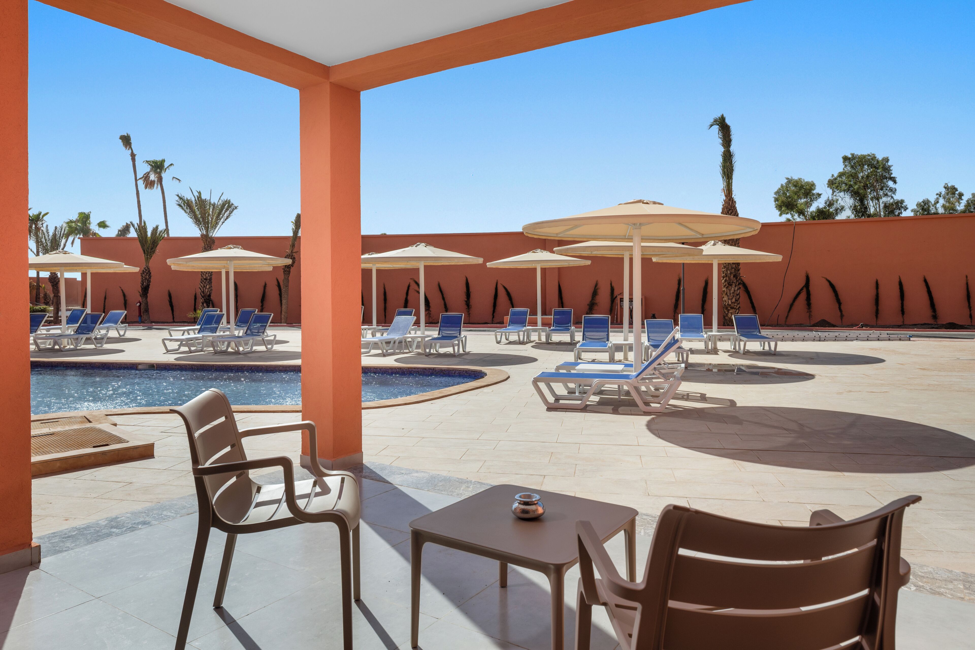 A poolside area with lounge chairs, umbrellas, and a small table.