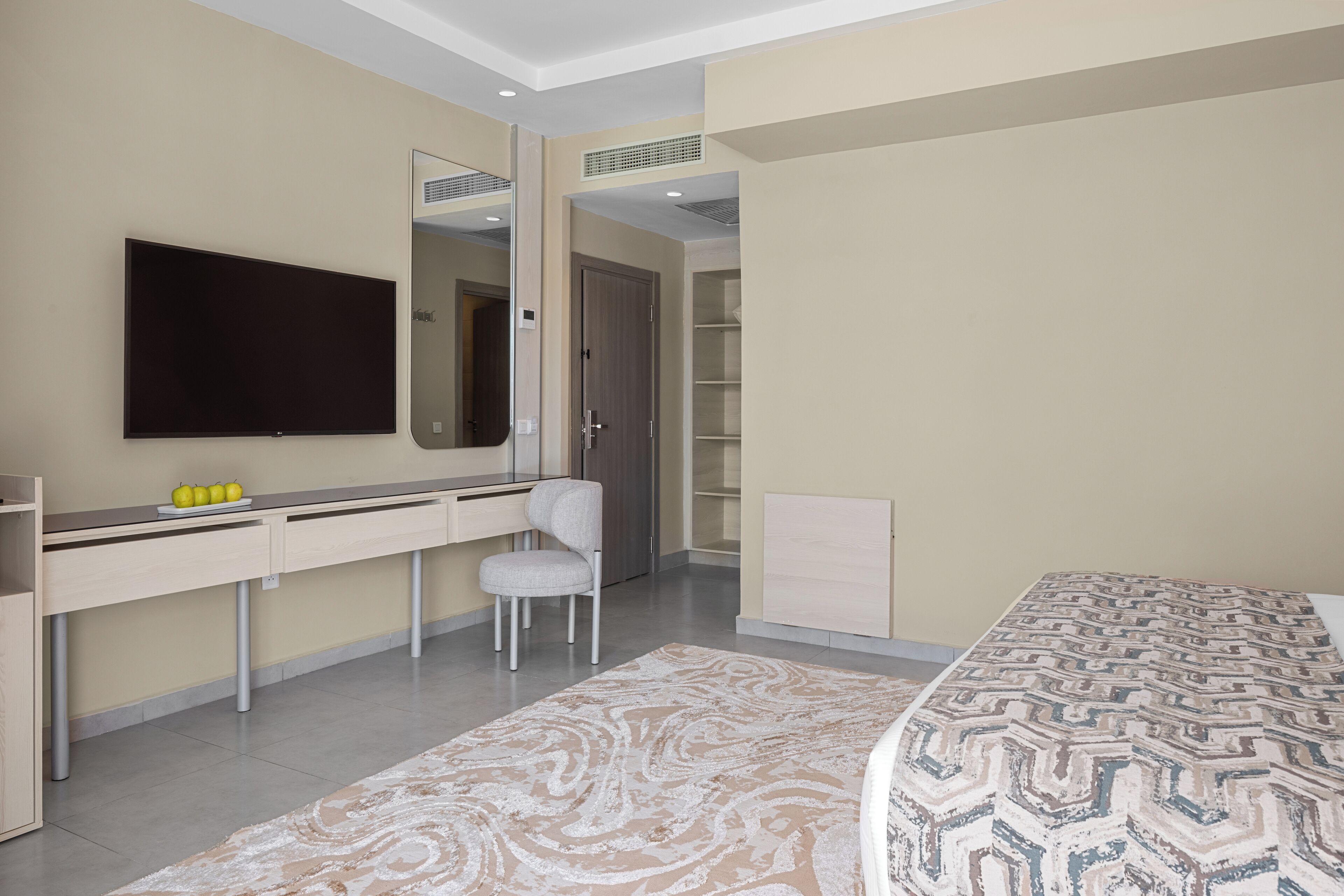 Ein modernes Schlafzimmer mit Bett, Schreibtisch, Stuhl, Fernseher und Kleiderschrank.