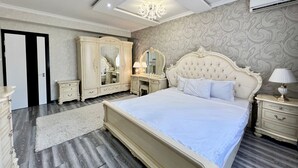A bedroom with a large bed, a wardrobe, a dressing table, and a mirror. - Golden house (Tashkent)