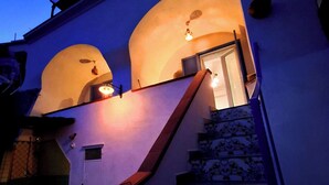 Un bâtiment doté d’un escalier menant à une entrée, une porte et une petite fenêtre.
